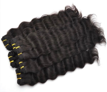 Stack of black wavy human hair extensions with yellow ties on a white background